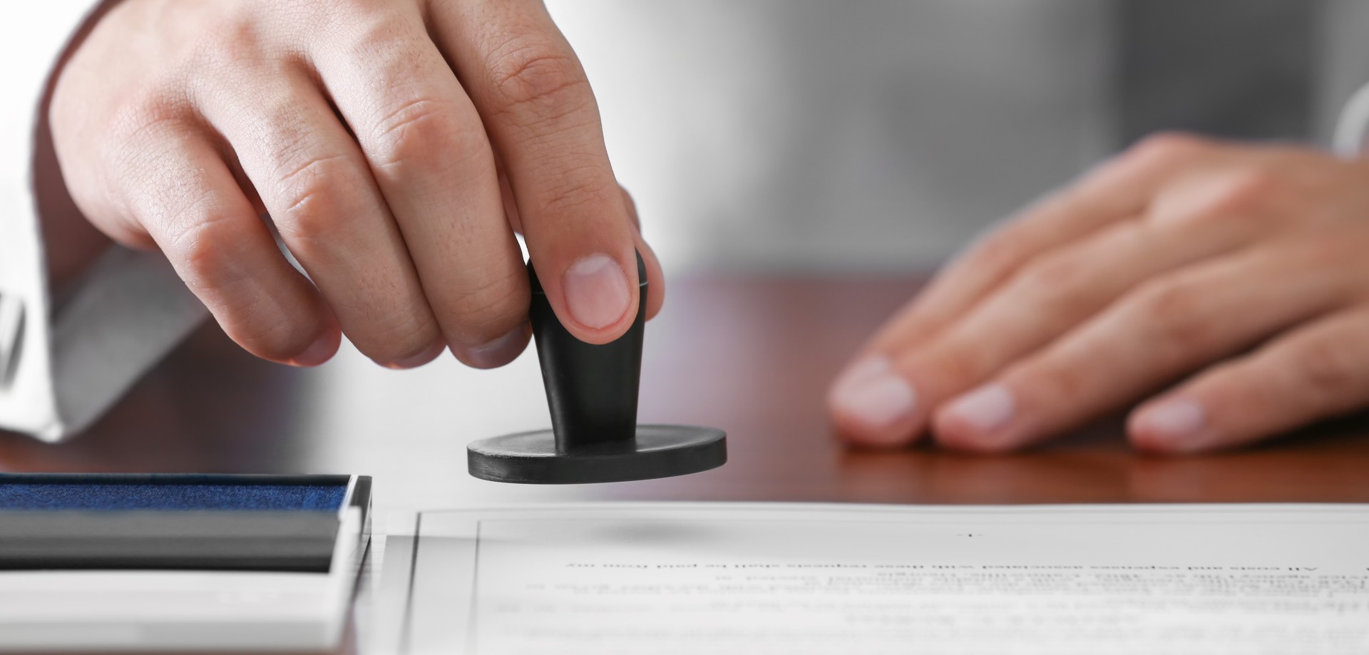 Close-up of a hand that is lowering a stamp onto a piece of paper